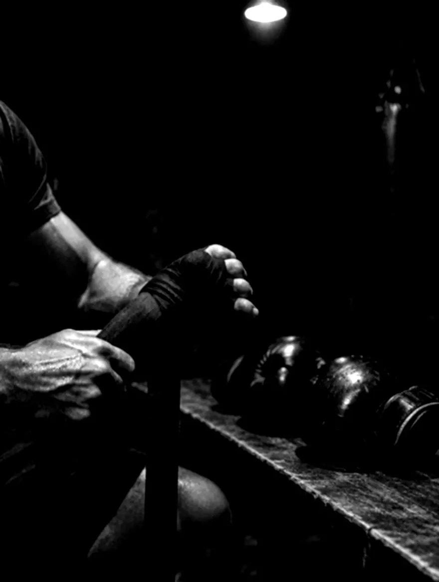 Manos vendándose junto a unos guantes de boxeo
